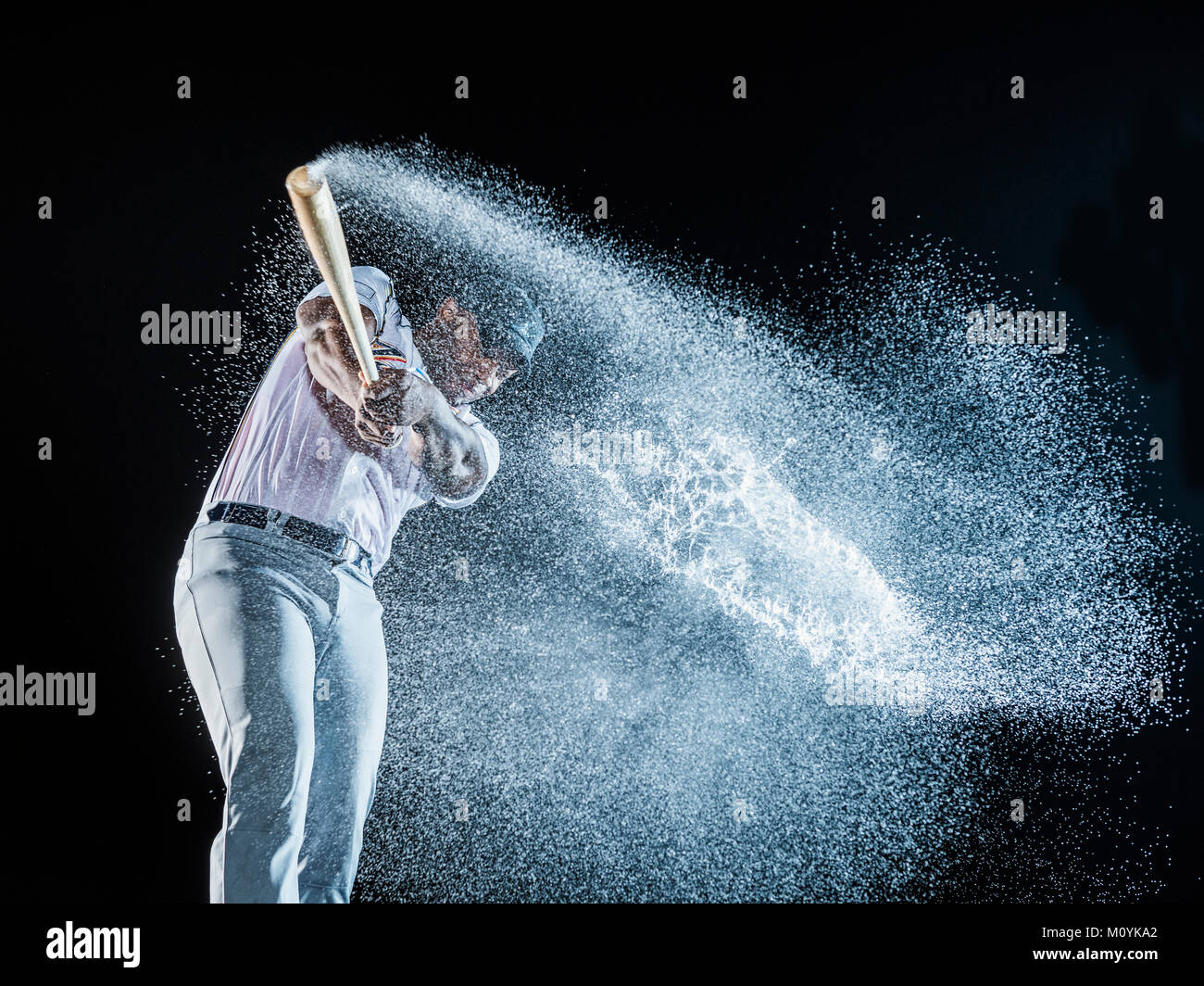 Water splashing from swinging bat of black baseball player Stock Photo
