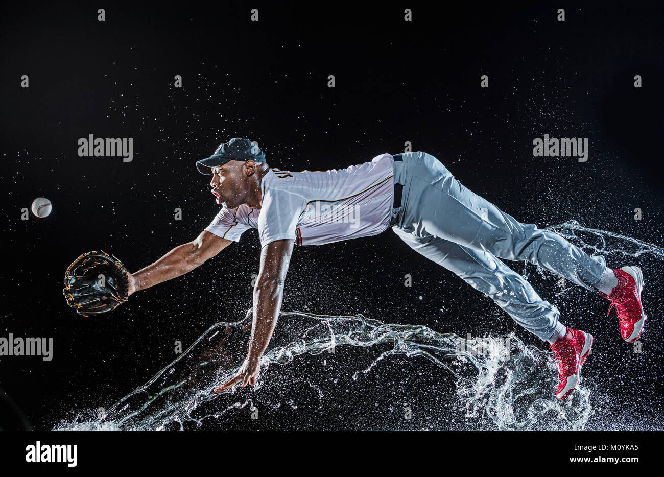 Water splashing on diving black baseball player Stock Photo