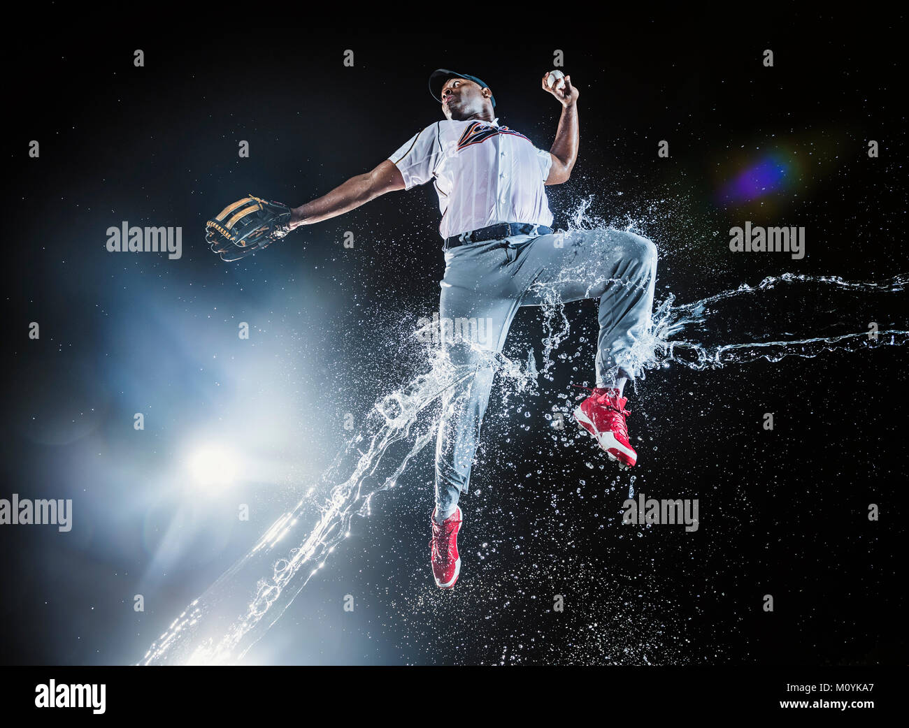 Water splashing on jumping black baseball player Stock Photo