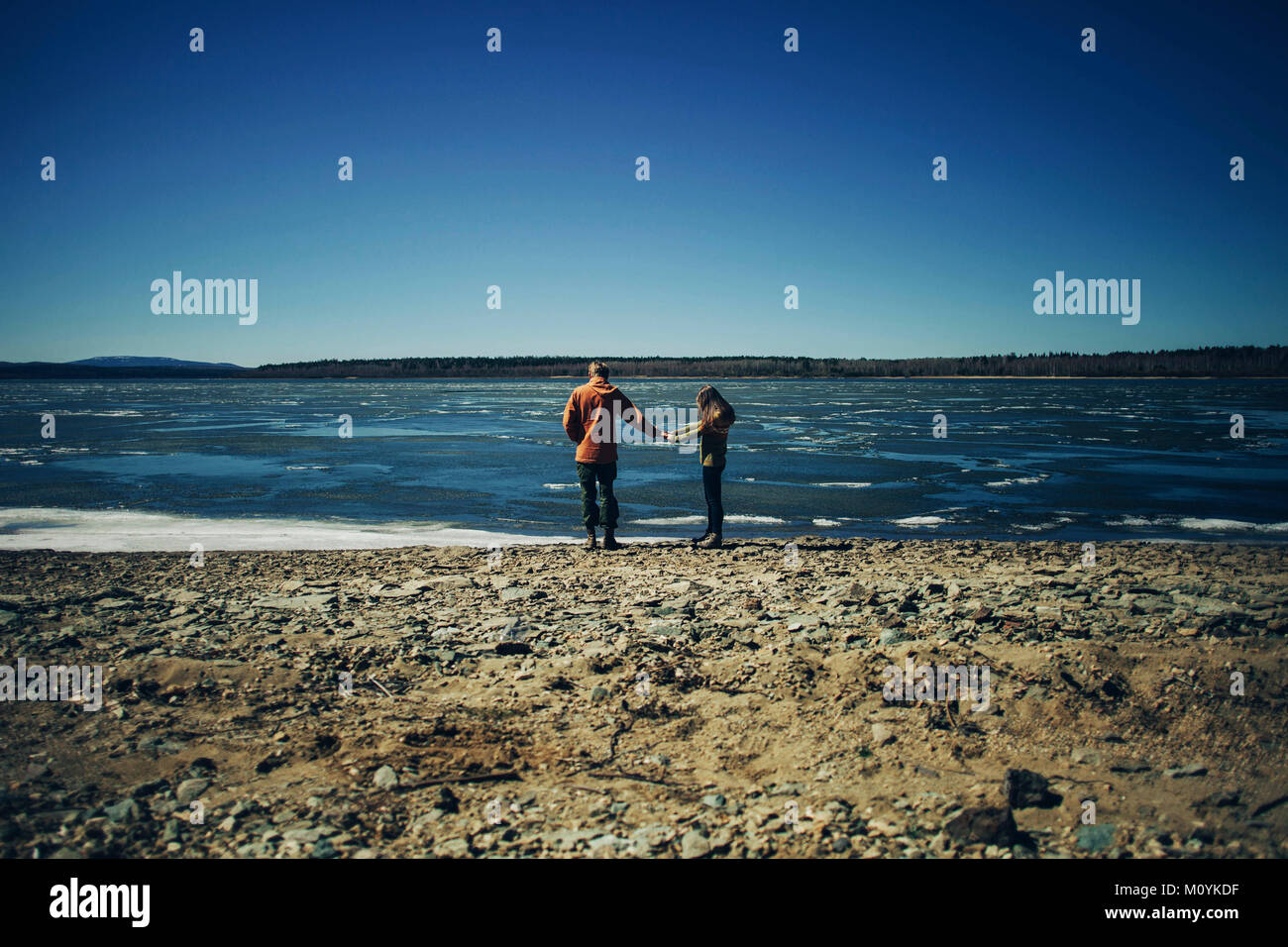 Distant Caucasian couple holding hands on beach Stock Photo