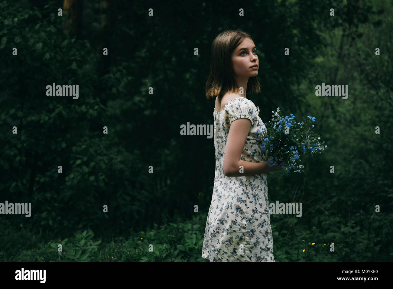 Caucasian woman holding flowers in forest Stock Photo