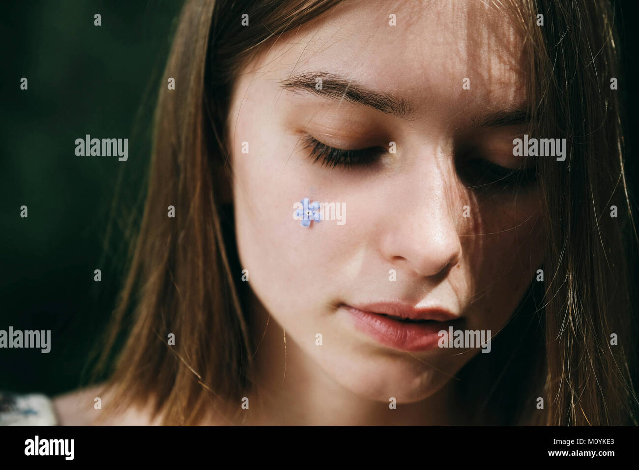 Caucasian woman with flower jewelry on cheek Stock Photo