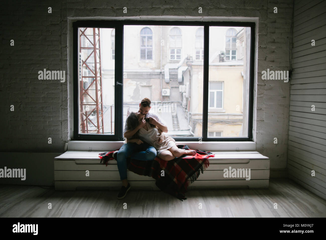 Caucasian couple kissing on bench near window Stock Photo