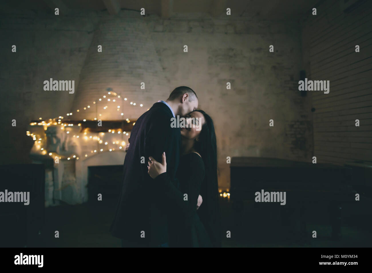 Caucasian couple hugging near fireplace Stock Photo