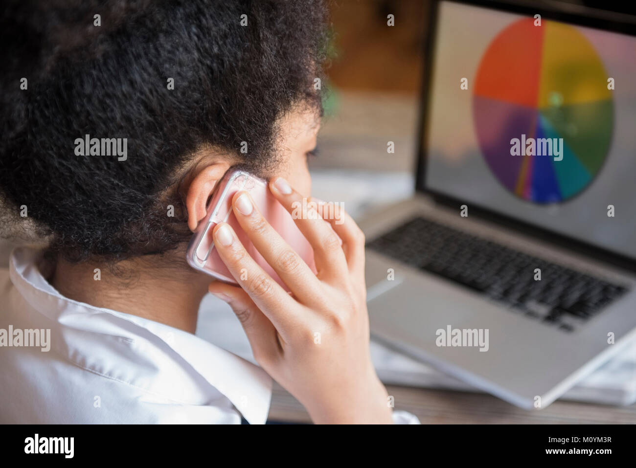 African American woman talking on cell phone and using laptop Stock Photo