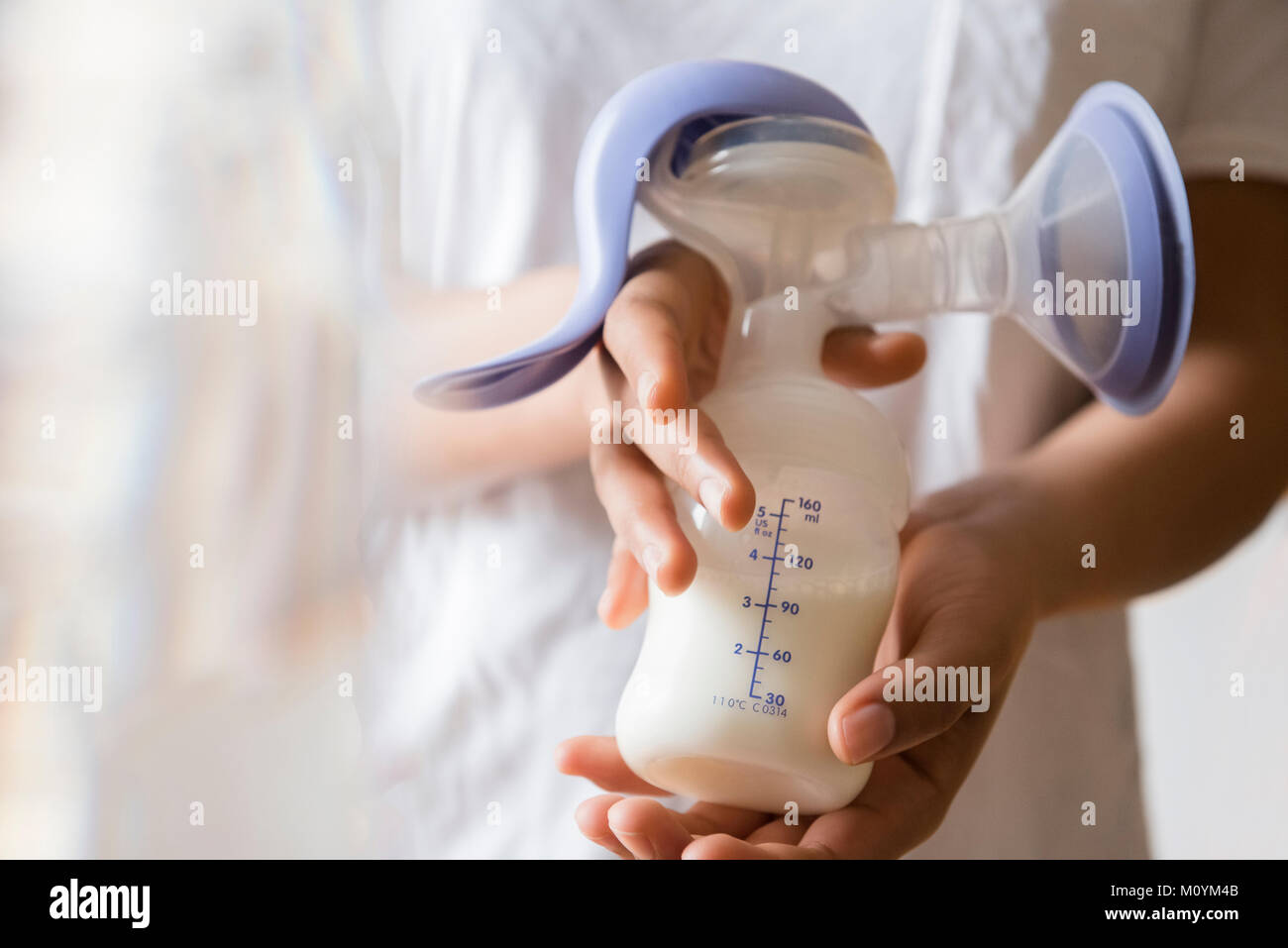 African American woman holding milk in breast pump Stock Photo