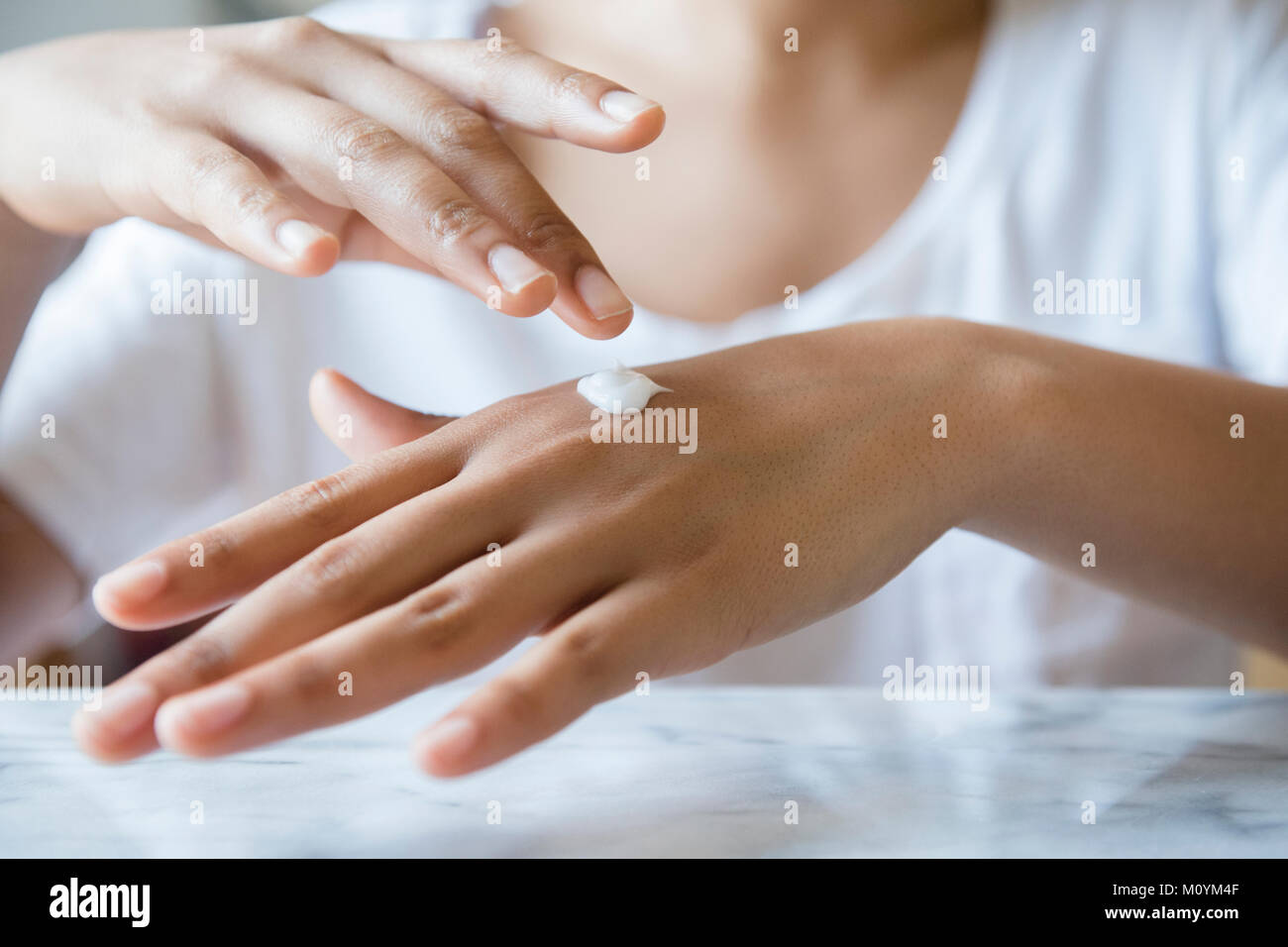 African American woman applying lotion to hand Stock Photo