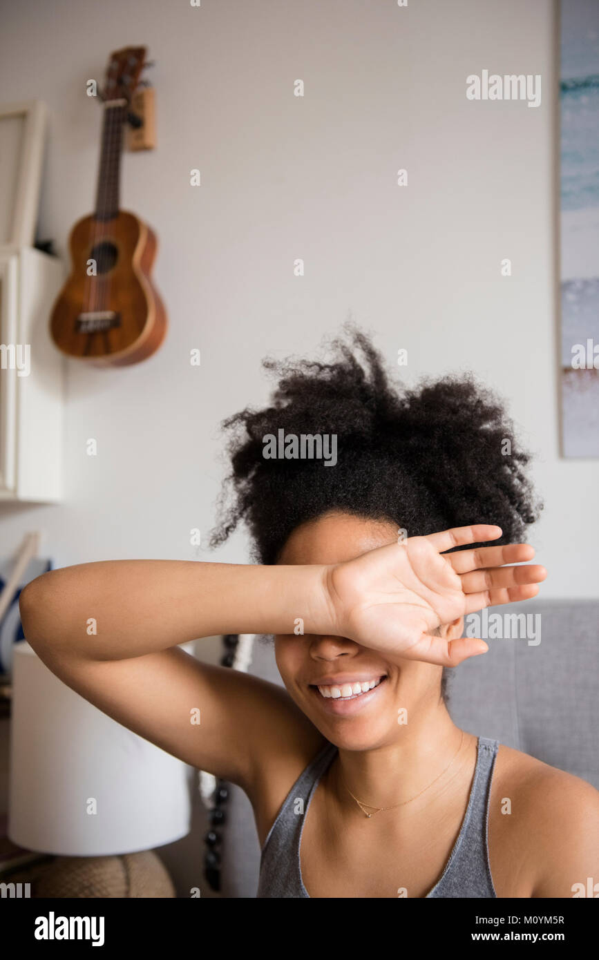 Smiling African American woman covering eyes with arm Stock Photo