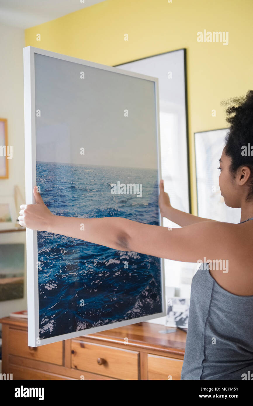 African American woman admiring large photograph of ocean Stock Photo
