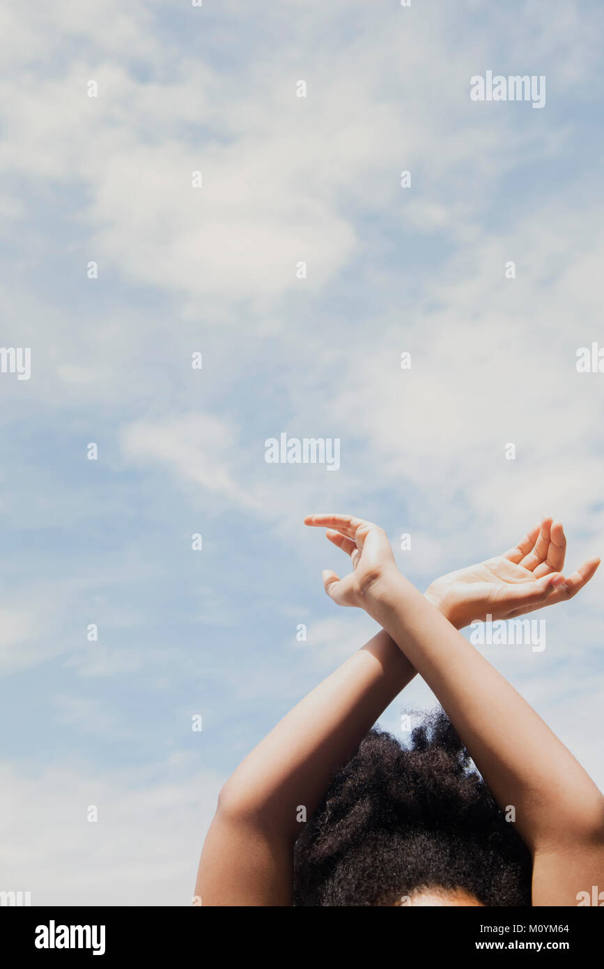 African American woman with arms raised to clouds Stock Photo
