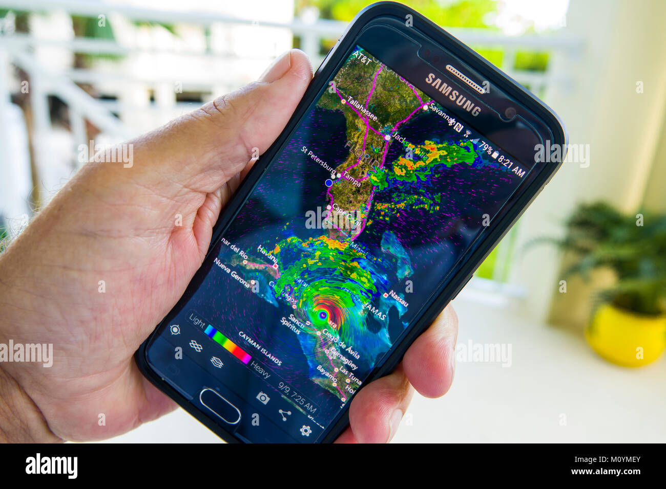 Following and tracking a hurricane Irma warning on tv television and a cellphone hand held device smartphone Stock Photo