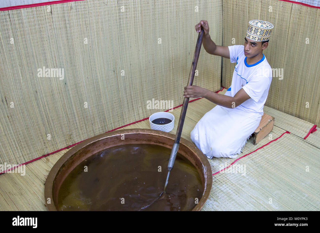 Nizwa, Oman, 26th May, 2016: worker at a halwa factory mixing a pot of halwa Stock Photo