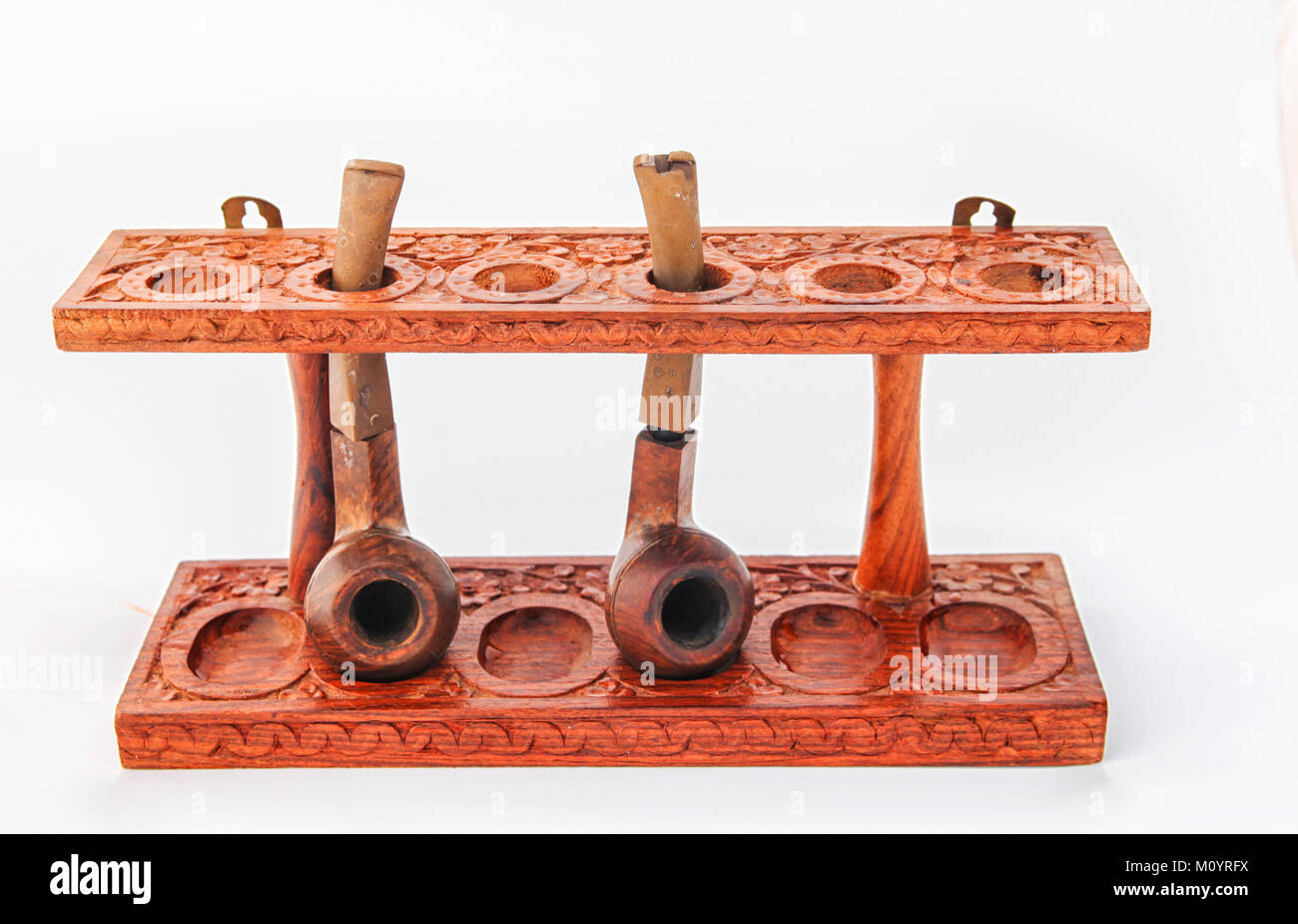 Beautufully carved antique wooden pipe stand with two pipes Stock Photo