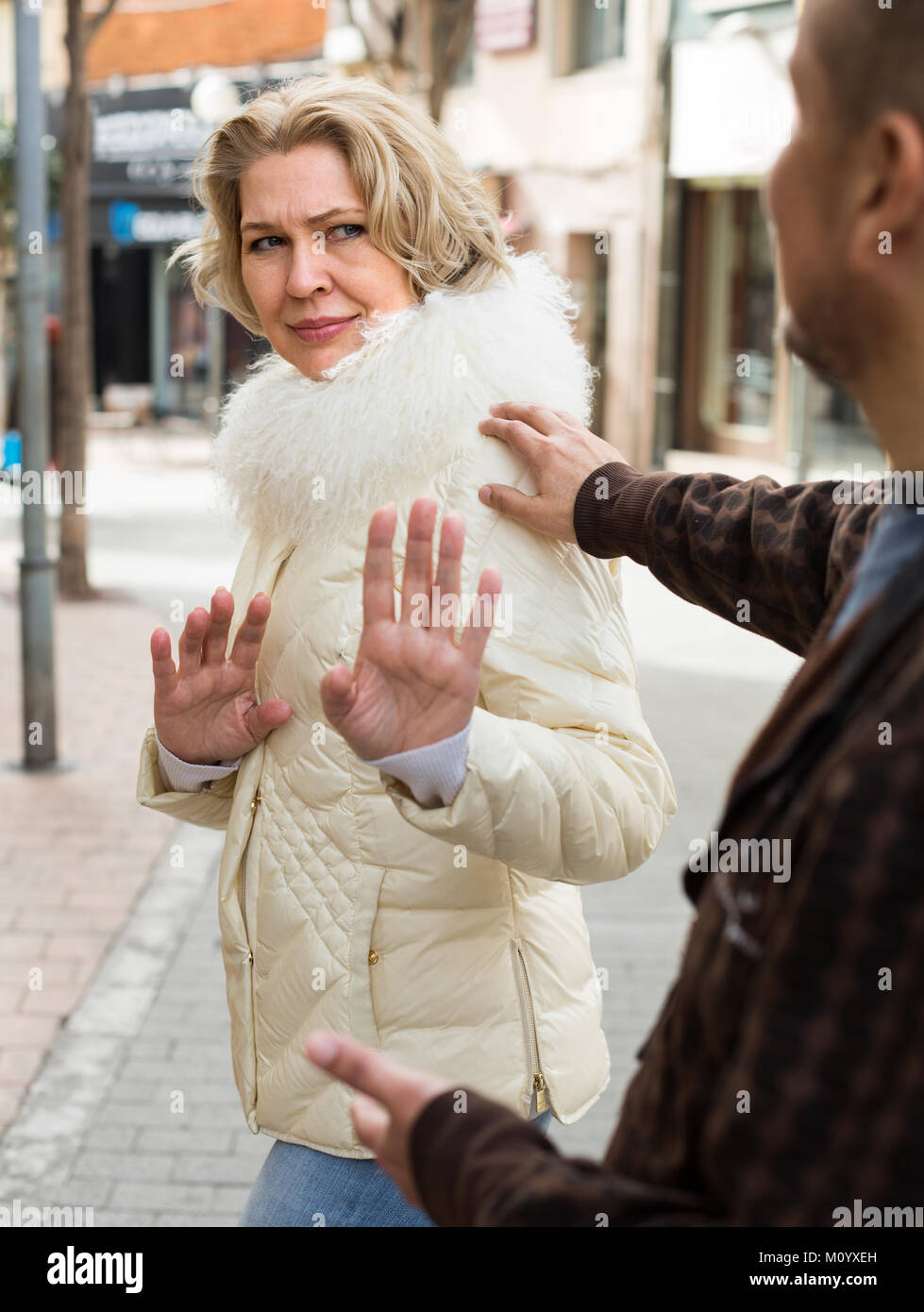 Impatient senior woman asking man not to bother her outdoor Stock Photo