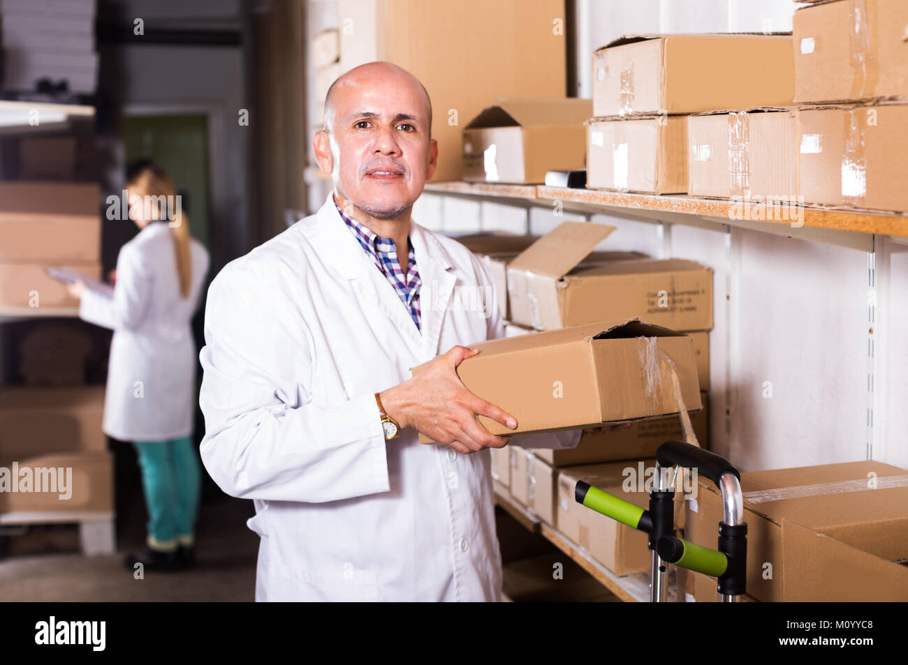 Adult man worker performing loading works in storage Stock Photo - Alamy