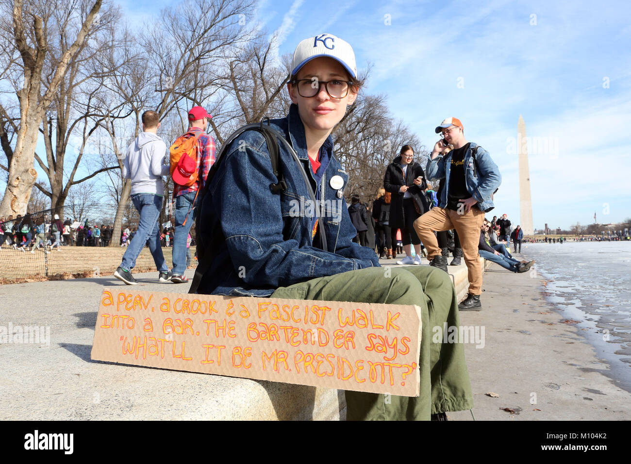 Washington Dc, DC, USA. 20th Jan, 2018. MIRIAM JULIANNA SUTTON sits near the ice on the Washington Mall as she listens to speeches during the 2018 Women's March on Washington. Her sign reads 'A perv, a crook and a Facist walk into a bar. The bartender says What'll it be Mr. President? Credit: Krista Kennell/ZUMA Wire/Alamy Live News Stock Photo