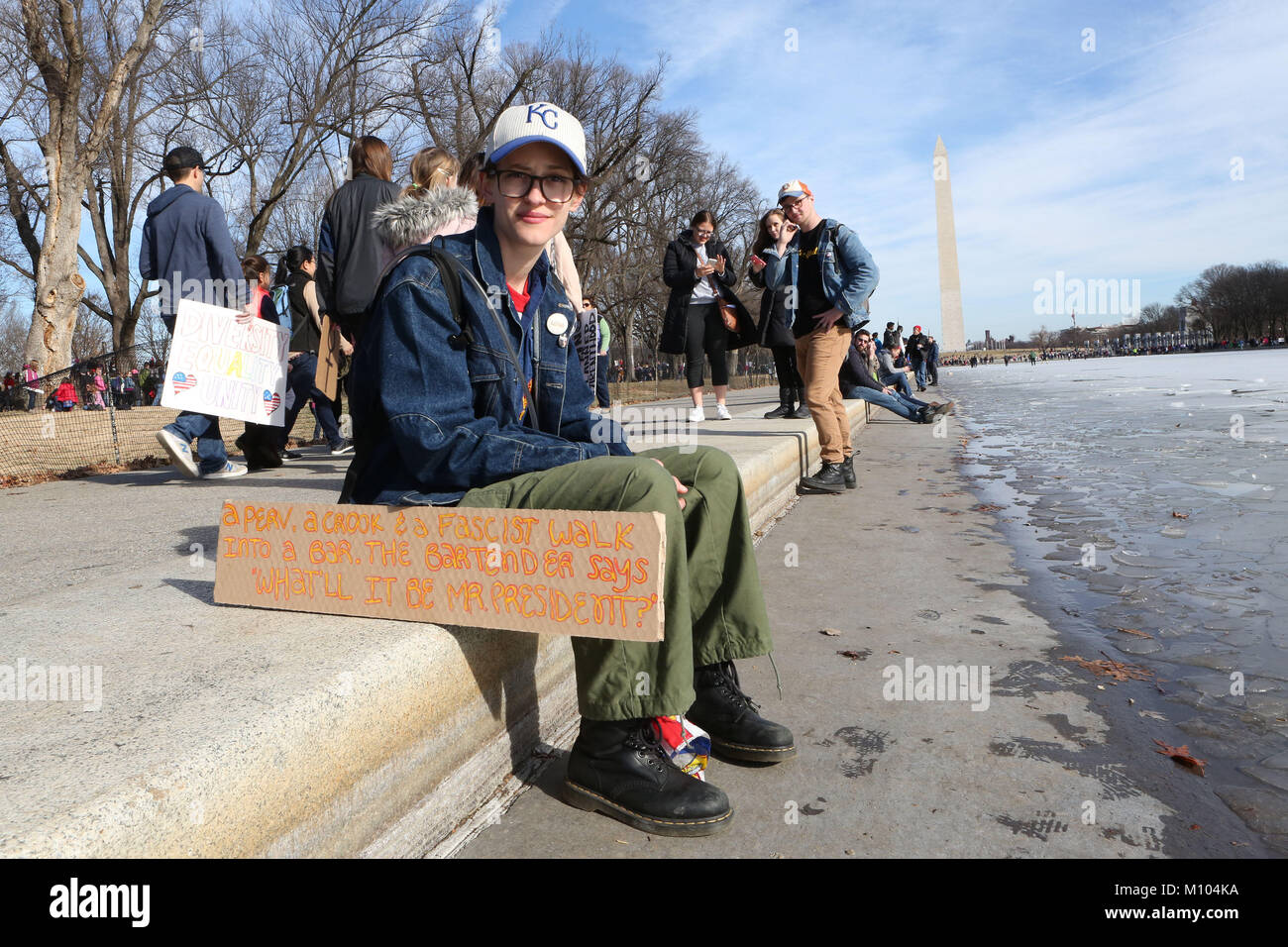 Washington Dc, DC, USA. 20th Jan, 2018. MIRIAM JULIANNA SUTTON sits near the ice on the Washington Mall as she listens to speeches during the 2018 Women's March on Washington. Her sign reads 'A perv, a crook and a Facist walk into a bar. The bartender says What'll it be Mr. President? Credit: Krista Kennell/ZUMA Wire/Alamy Live News Stock Photo