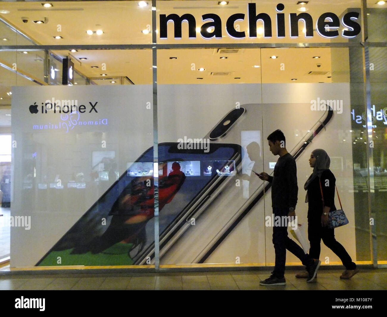 January 22, 2018 - Kuala Lumpur, Kuala Lumpur, Malaysia - A couple is seen passing by the Apple Machine store at Kuala Lumpur...Kuala Lumpur or commonly known as KL is the national capital for Malaysia and is the fastest growing metropolitan regions in South-East Asia. The urban city is also well known to the world for tourism and shopping. Kuala Lumpur has a great public transportation for people travel around the city. (Credit Image: © Faris Hadziq/SOPA via ZUMA Wire) Stock Photo