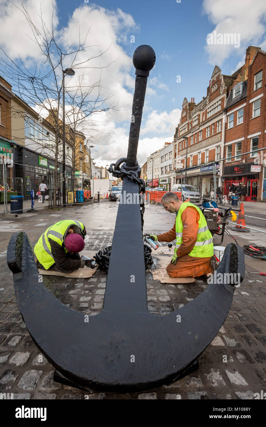 London, UK. 25th Jan, 2018. The iconic Deptford Anchor is finally returned to its original place at the south end of Deptford High Street after being removed in 2013 for high street redevelopment works. Seen here being painted on its new cobblestone base shortly after being lifted into position. The Anchor forms part of Deptford's rich maritime history. Credit: Guy Corbishley/Alamy Live News Stock Photo