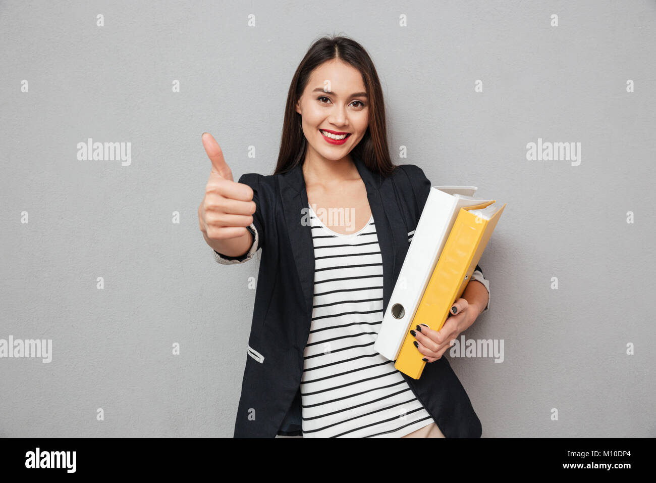 Happy asian business woman holding folders and showing thumb up while ...