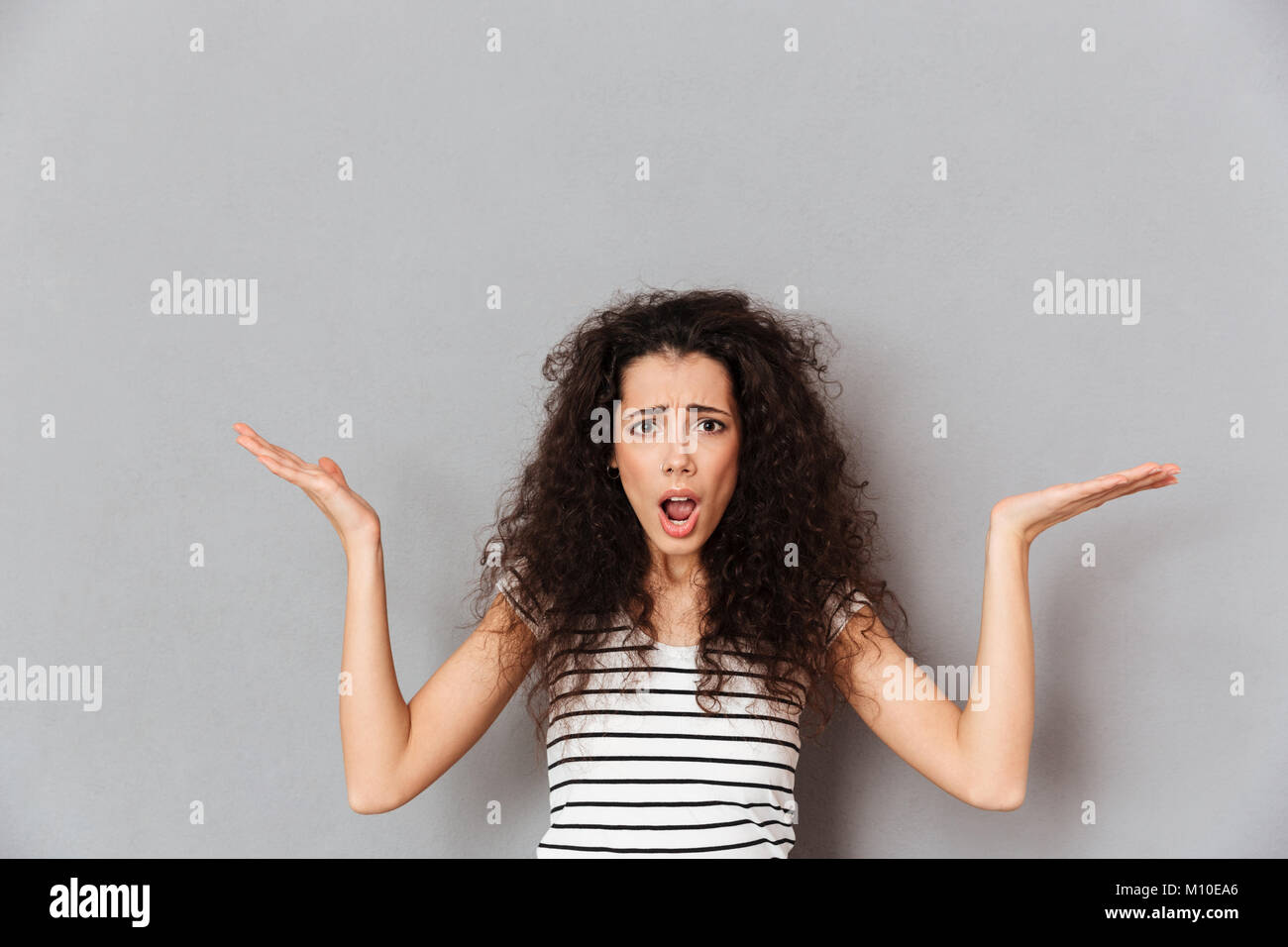 Pretty adult girl wearing striped tshirt throwing up hands meaning