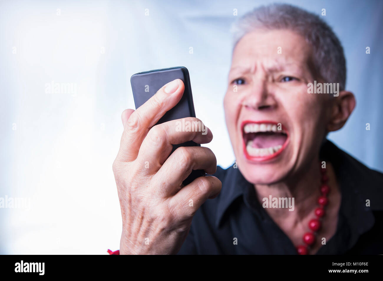 Old lady yelling at her cell phone Stock Photo - Alamy