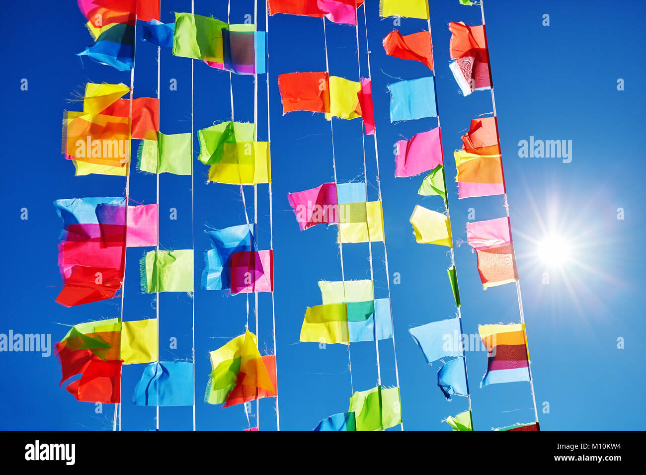 Colorful prayer flags against the sun and blue sky. Stock Photo