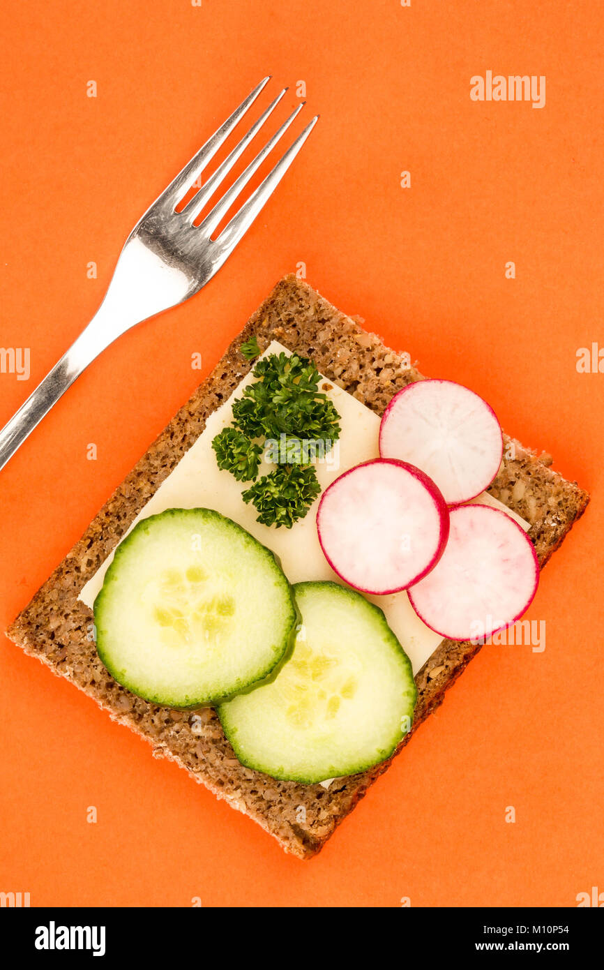 Cheese and Cucumber Open Face Rye Bread Sandwich With Radishes Against An Orange Background Stock Photo