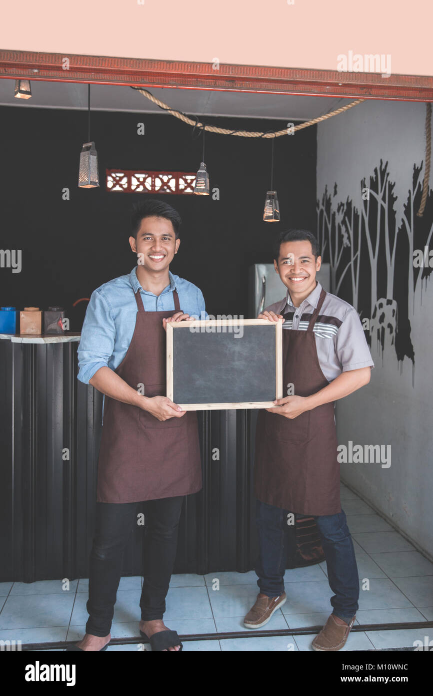 two coffee shop business partner holding blackboard sign in front of