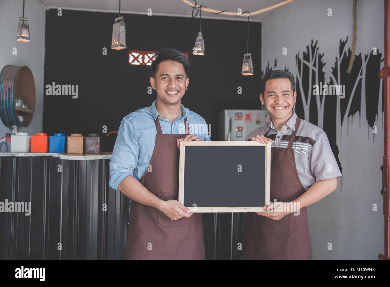 two coffee shop business partner holding blackboard sign in front of