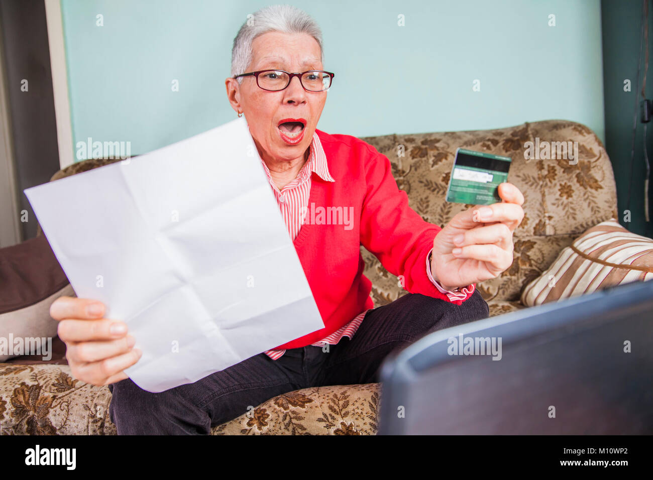 Senior old woman shocked by her credit card bill Stock Photo