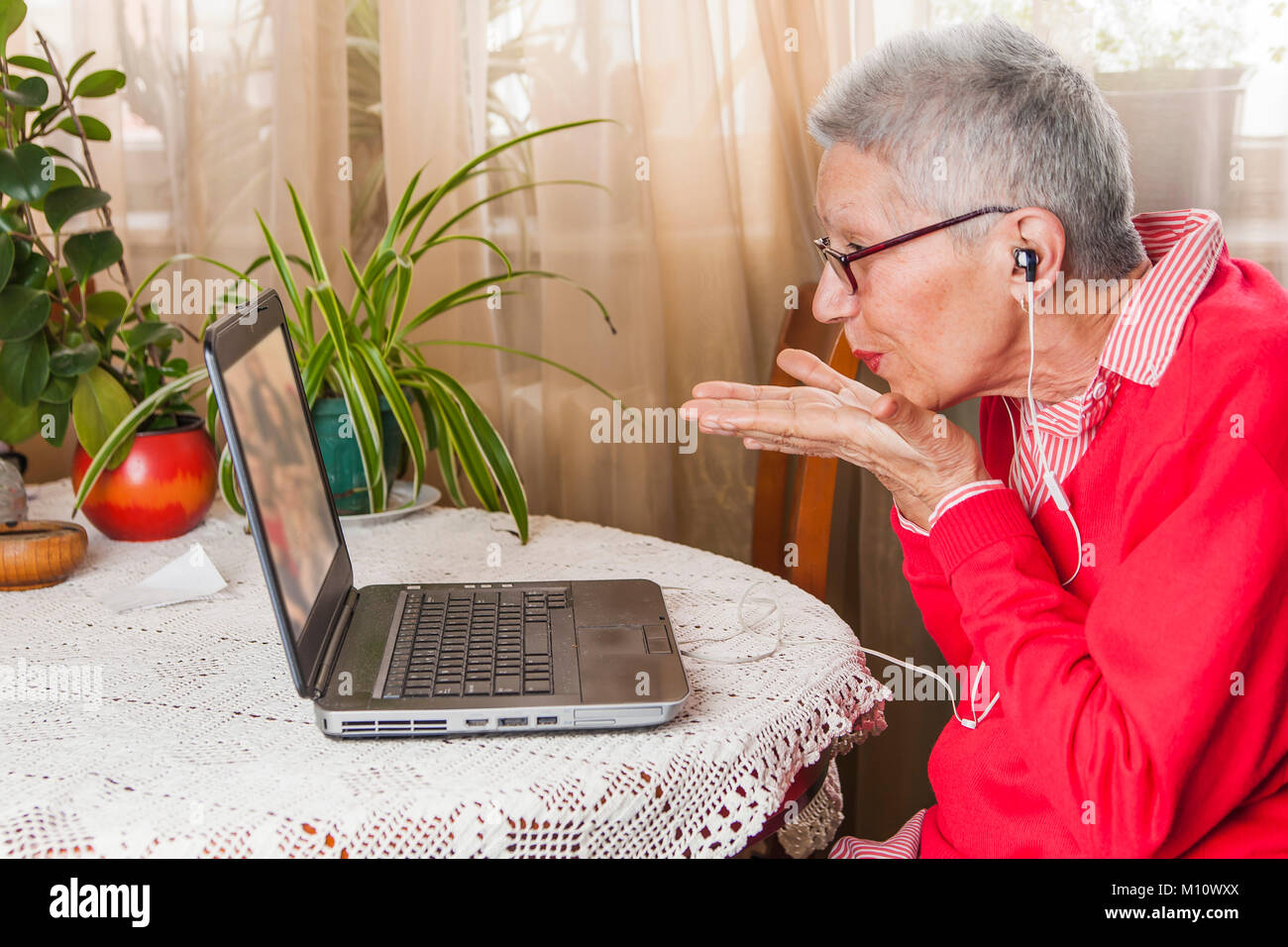 Grandma using laptop, camera and earphones for distant connections Stock Photo