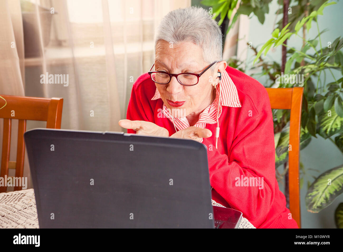 Grandma using laptop, camera and earphones for distant connections Stock Photo