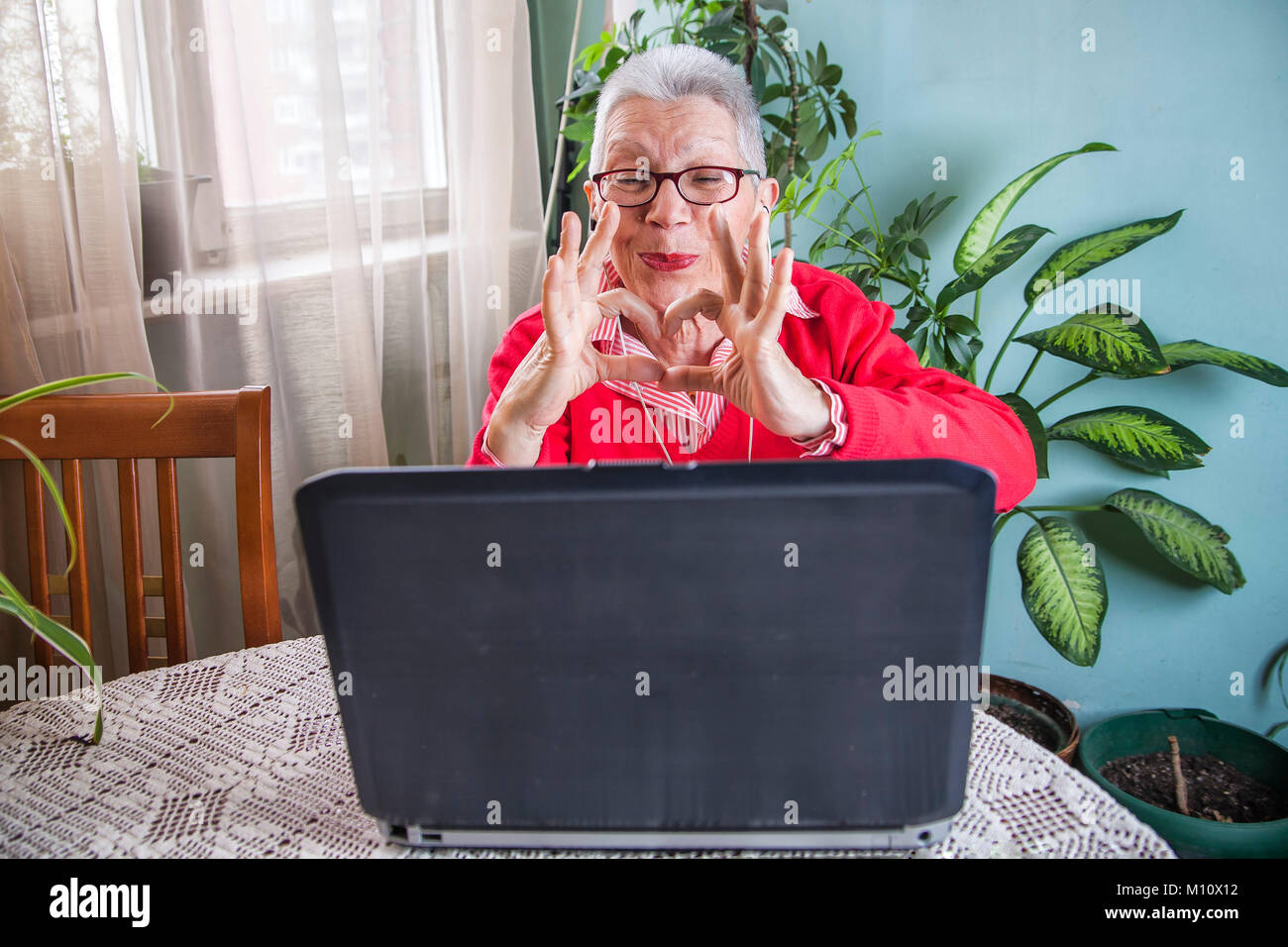 Grandma using laptop, camera and earphones for distant connections Stock Photo