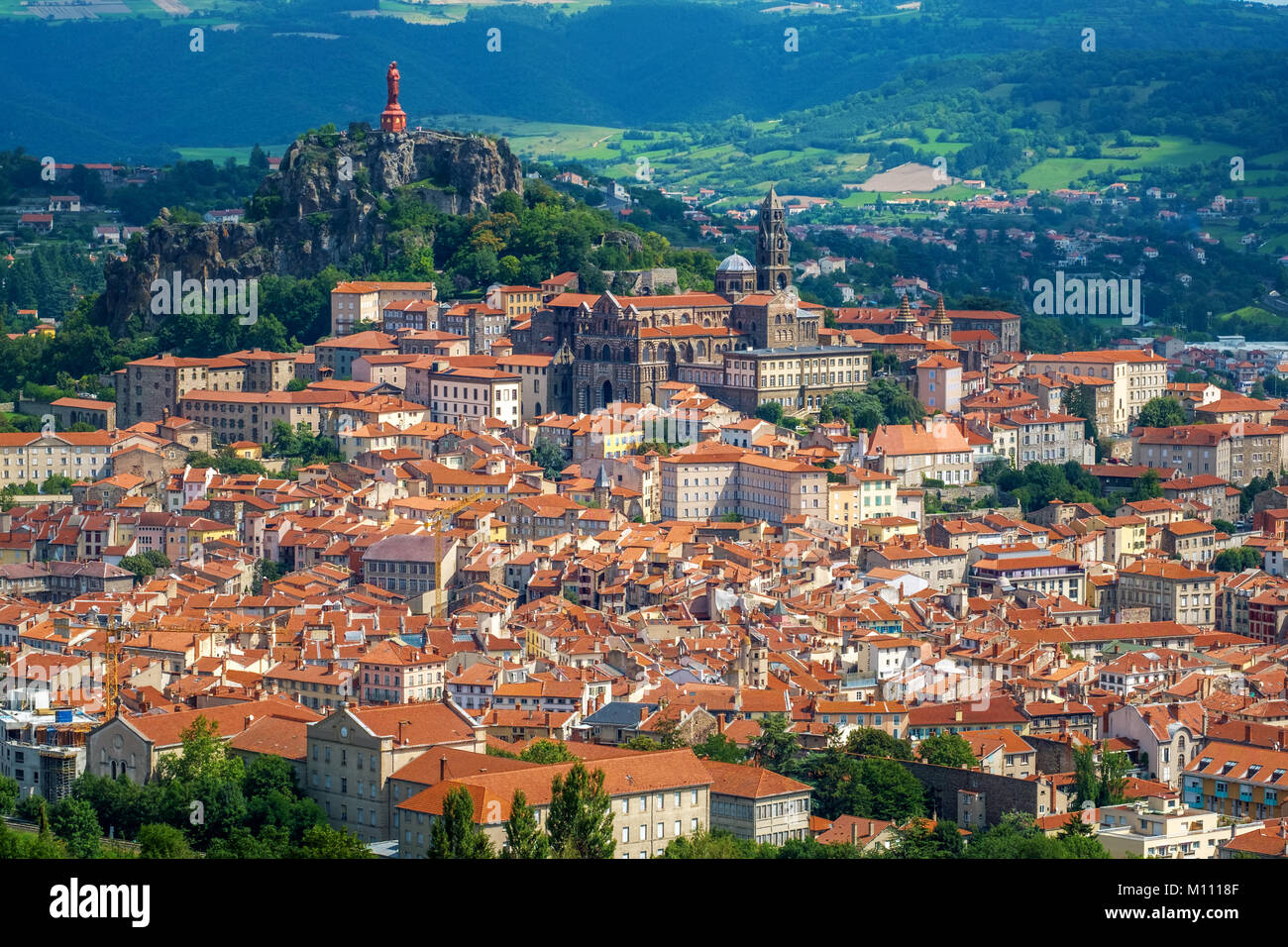 Panoramic view of red tiled roofs of Le Puy-en-Velay town, an important christian site in France, with Cathedral and the Notre Dame de la France Stock Photo