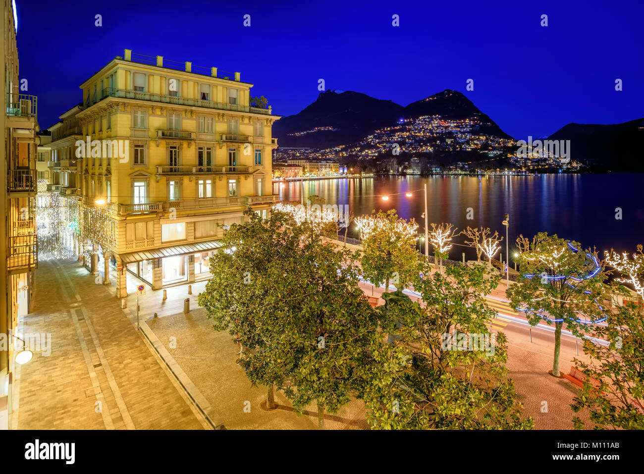 View of Lugano city, Monte Bre mountain and Lake Lugano, Switzerland, illuminated at night Stock Photo