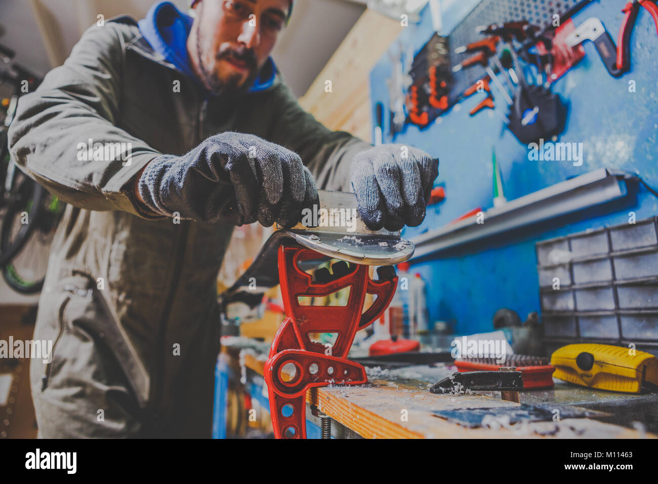 A male worker in a ski service repairs the sliding surface of