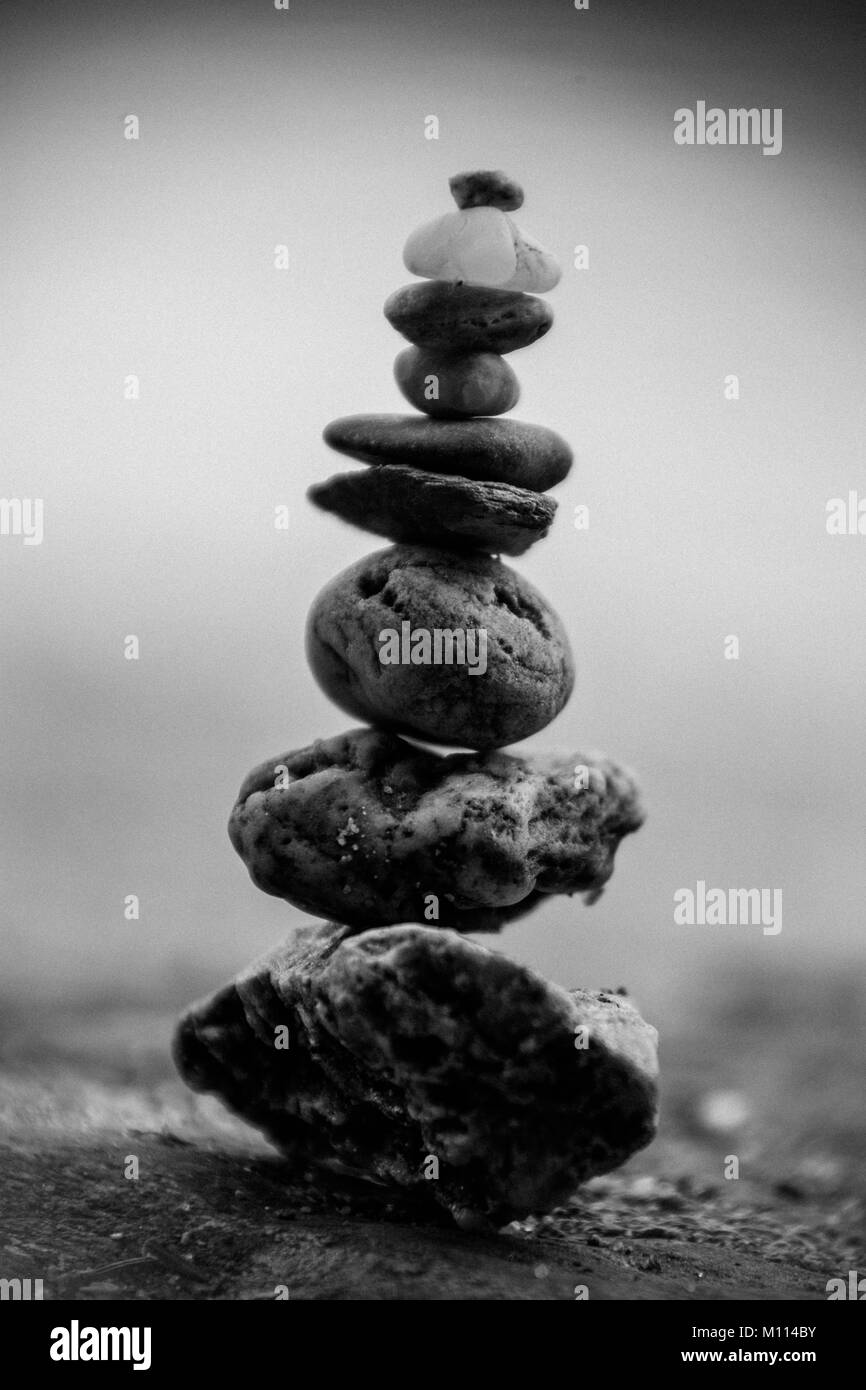 A black and white image of rocks and pebbles stacked up and balanced Stock Photo