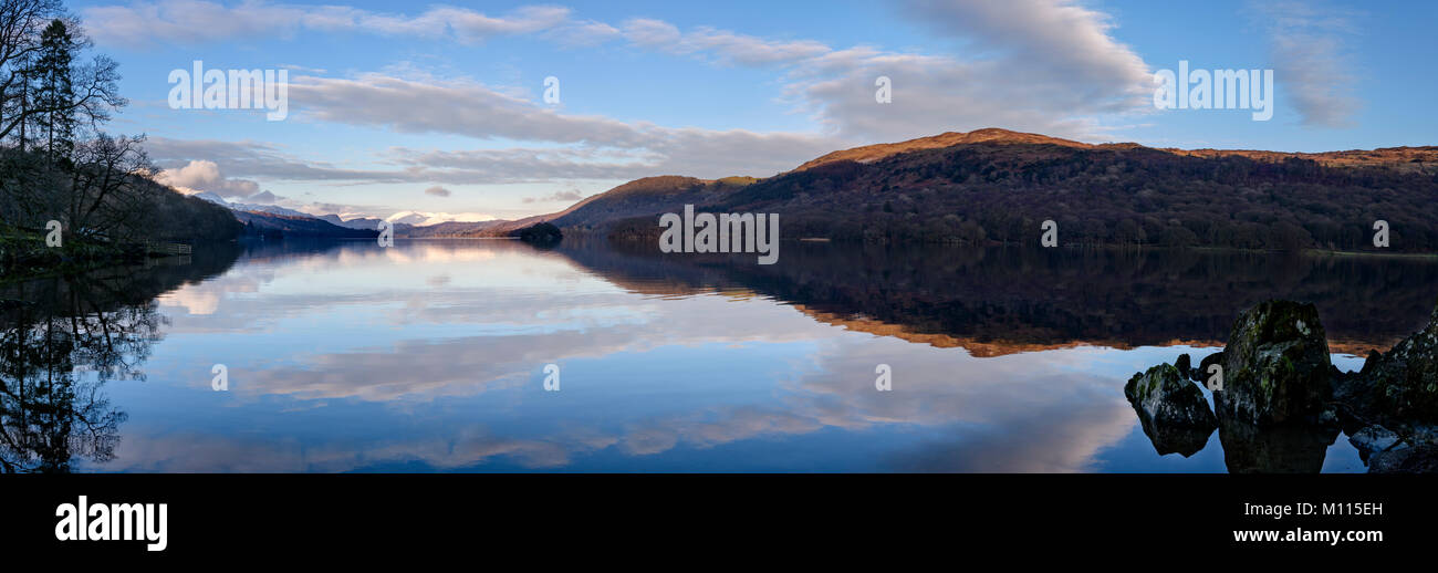 Panoramic view of a majestic looking Coniston Water. Clouds and sun-kissed fells perfectly reflected in the still water Stock Photo