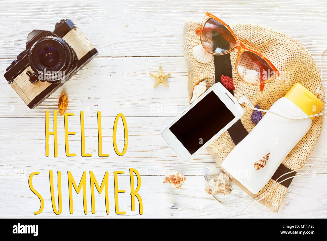 hello summer text, travel vacation flat lay concept. photo camera and hat sunscreen phone with empty screen and sunglasses on white wooden background, Stock Photo