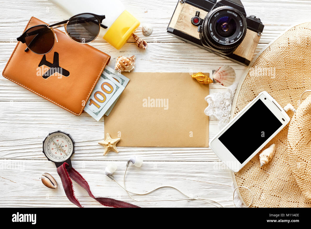 summer travel wanderlust concept, space for text, flat lay. empty card, camera  sunglasses compass passport money phone hat shells on white wooden bac Stock Photo