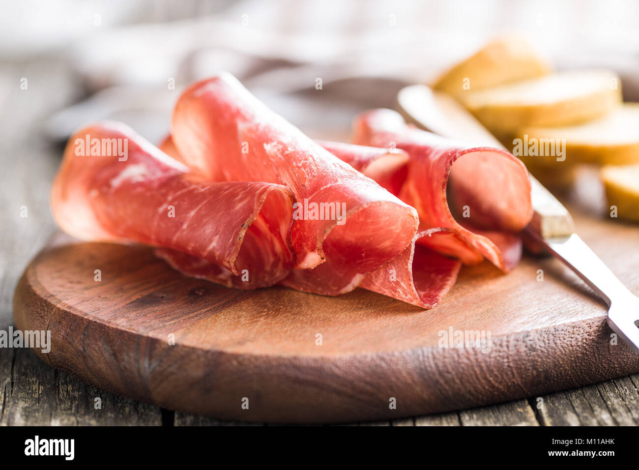 Sliced prosciutto crudo on cutting board. Stock Photo