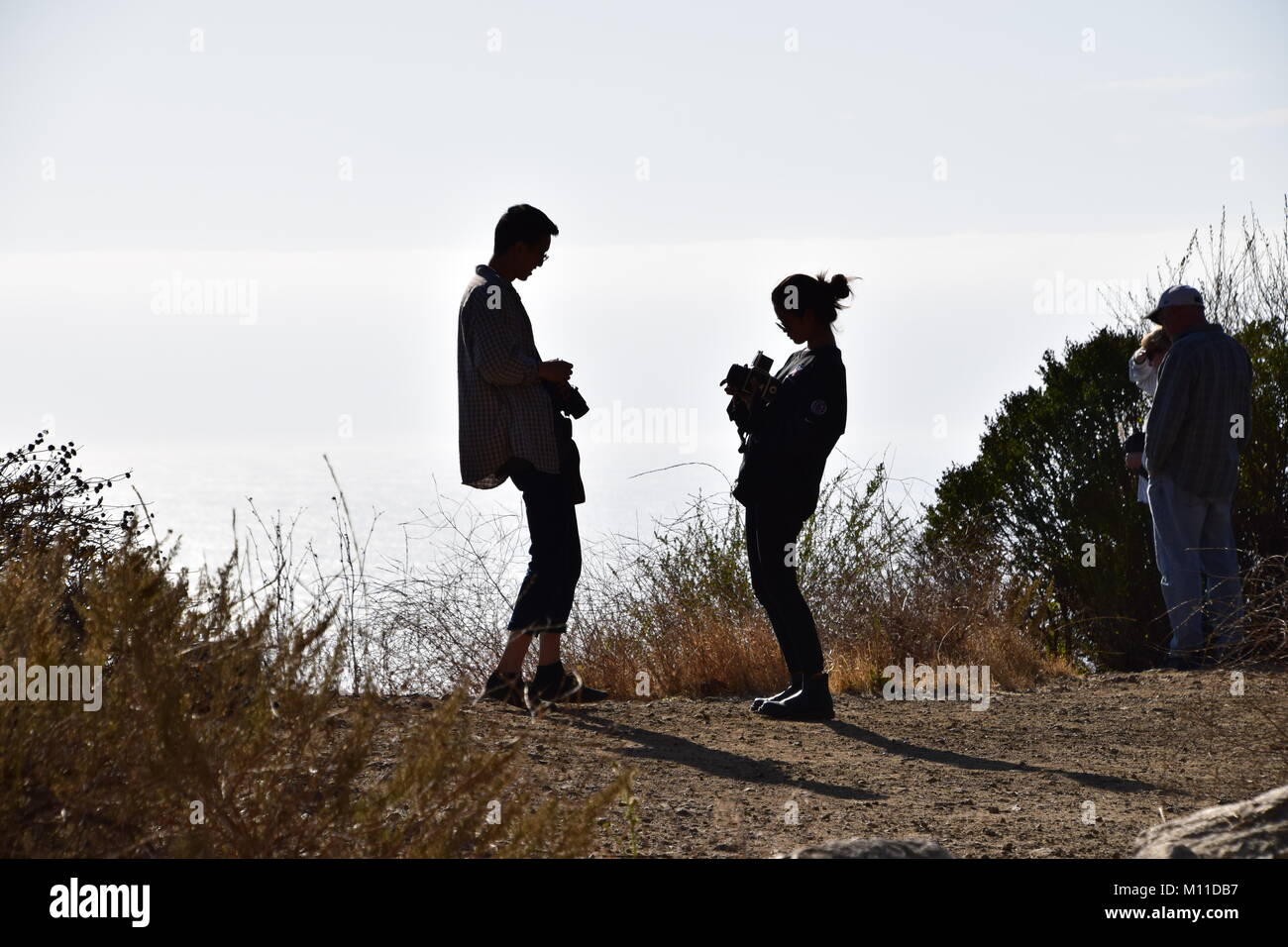 Silhouette of young couple with cameras on Highway 1, Big Sur, California Stock Photo