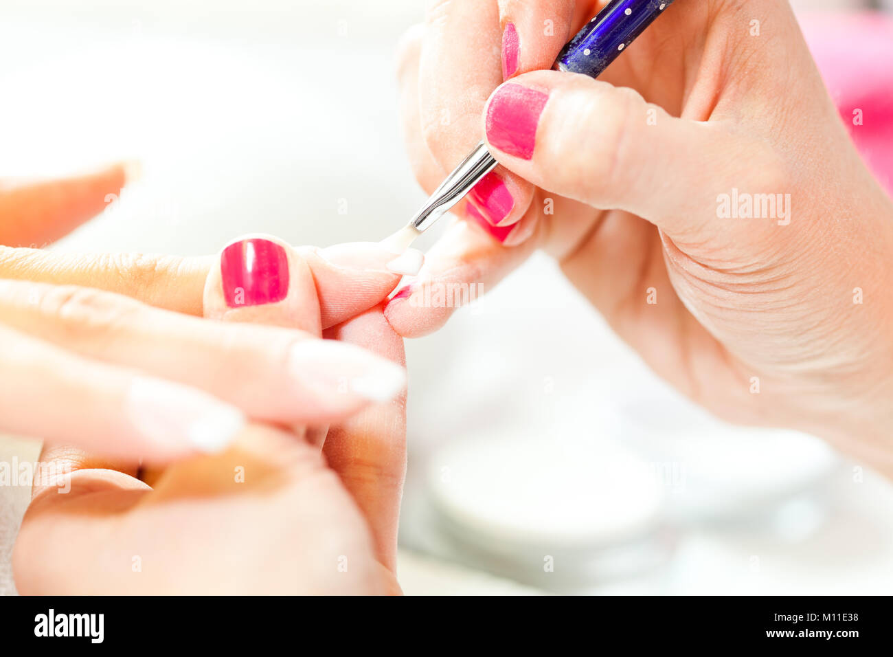 Process of nail treatment, applying white paint on fingernail Stock