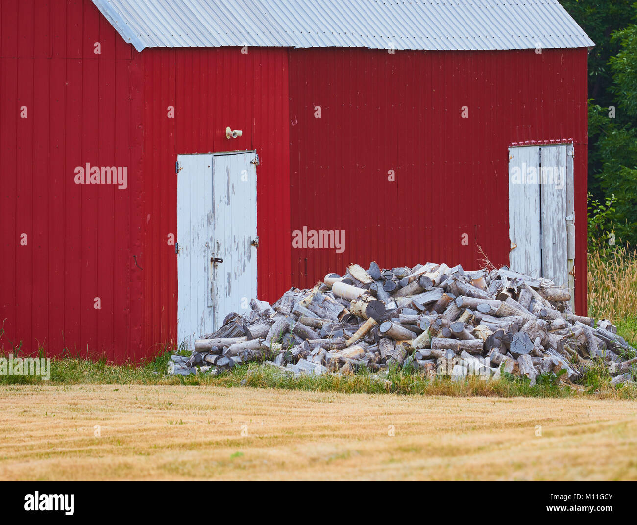 Pile of firewood outside traditional timber red barn, Nova Scotia