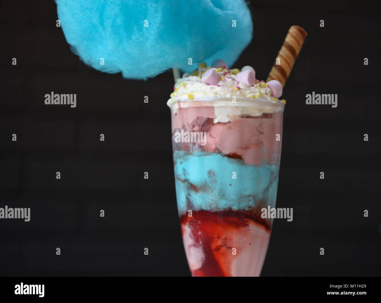 colorful food photography of a blue and pink ice cream sundae with strawberry and bubblegum flavored ice cream candy floss and on a black background Stock Photo