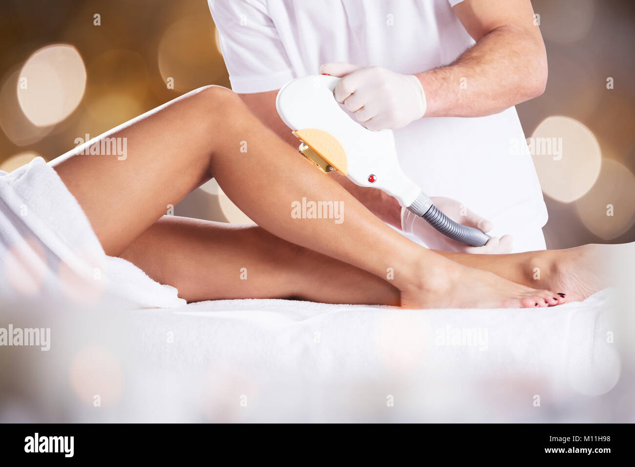 Close-up Of A Woman Getting Laser Treatment On Leg By Therapist Stock Photo