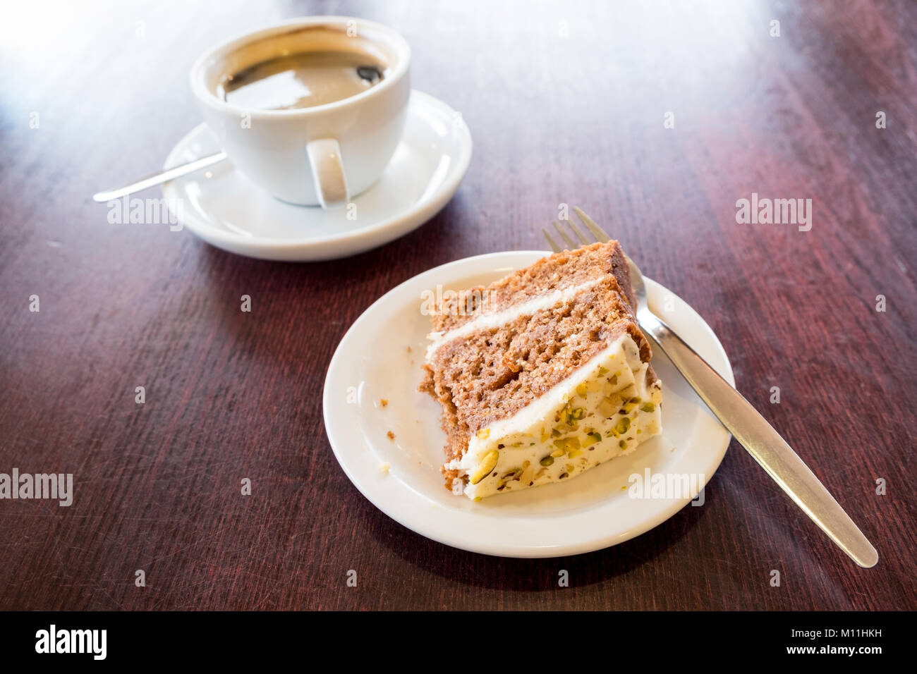 Black coffee and some partially eaten cake on a wooden table Stock Photo