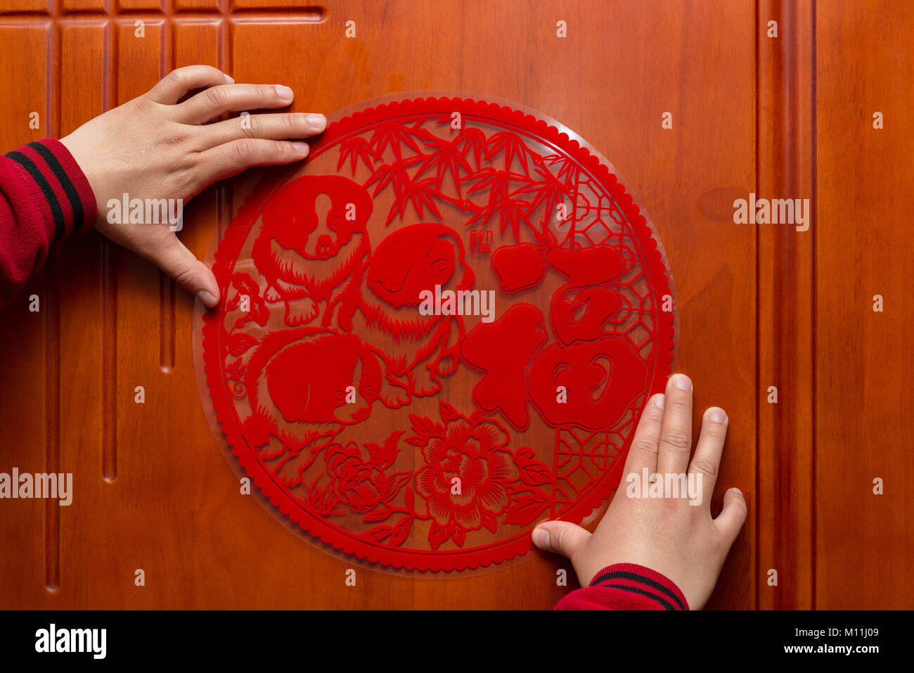 man sticking a Chinese New Year of the Dog 2018 to a door the Chinese means fortune Stock Photo
