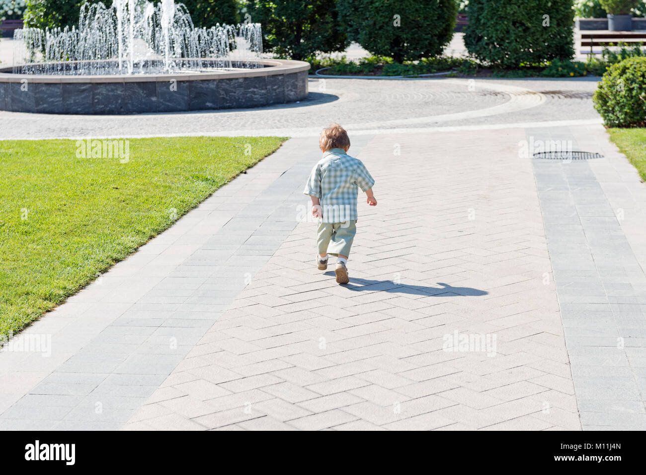 Three years old child in the park with water fountain and blue sky Stock Photo